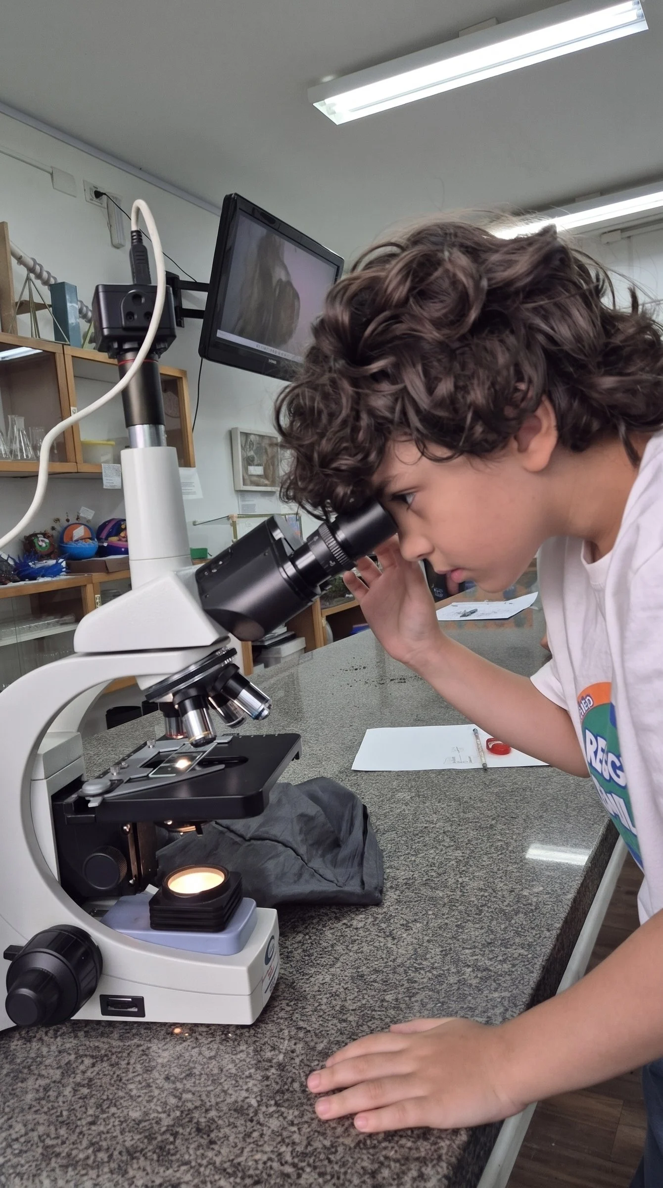 Aluno observa uma amostra no microscópio