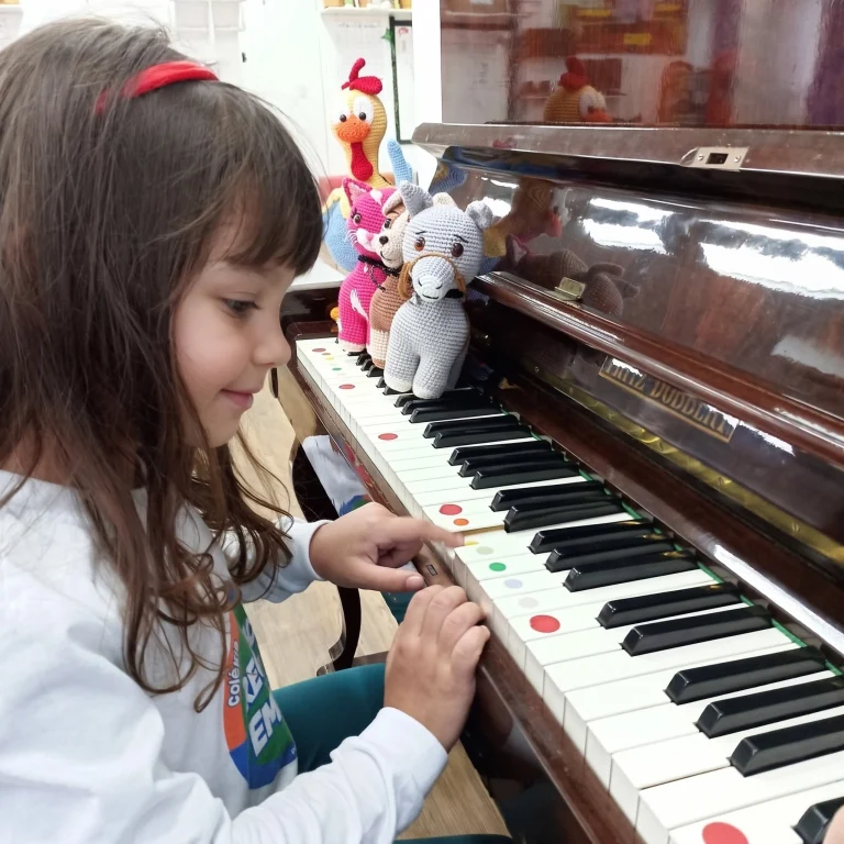 Aluna toca piano na aula de musicalização